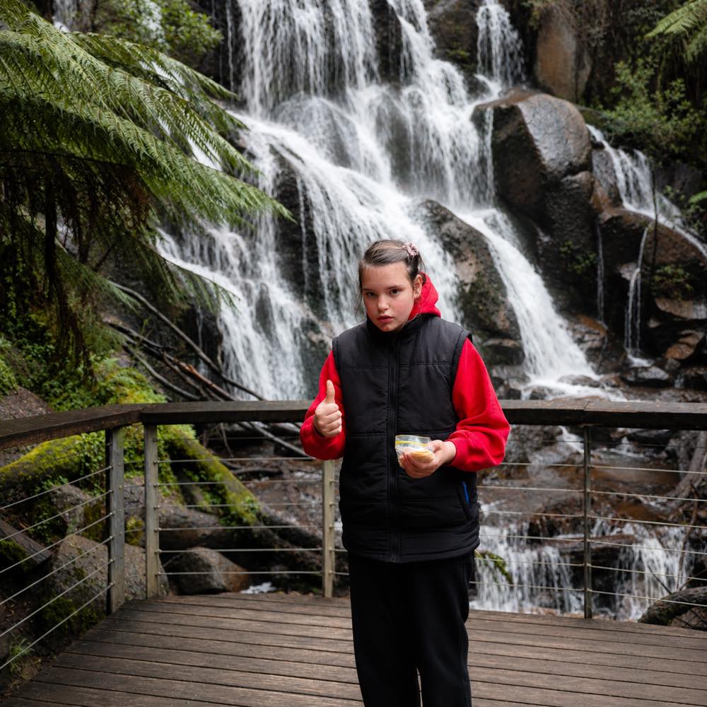 A participant standing in front of a waterfall in the ranges.